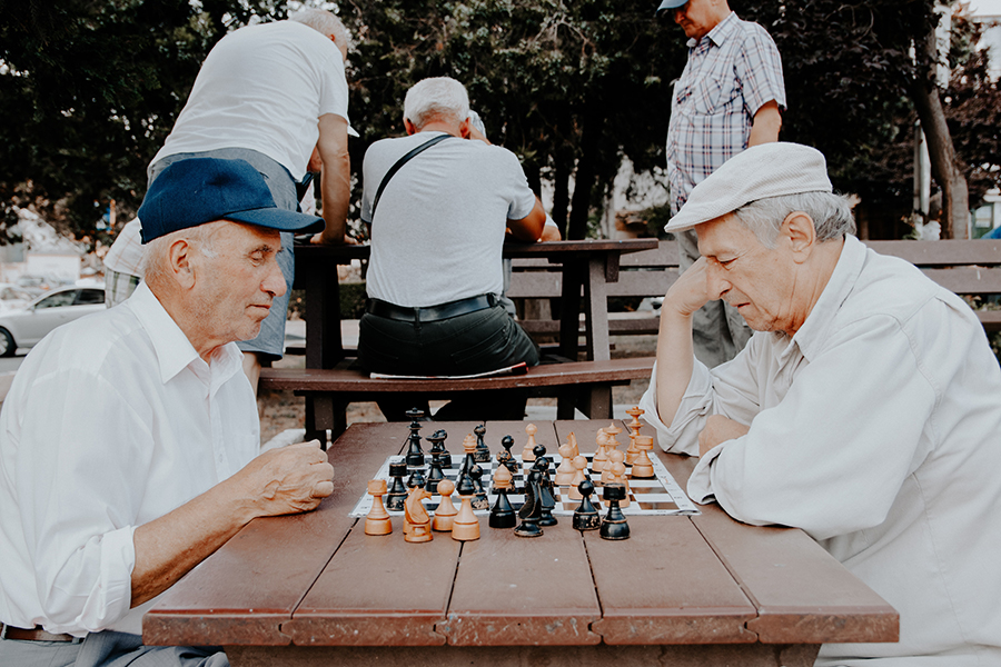 senior men playing chess in a park
