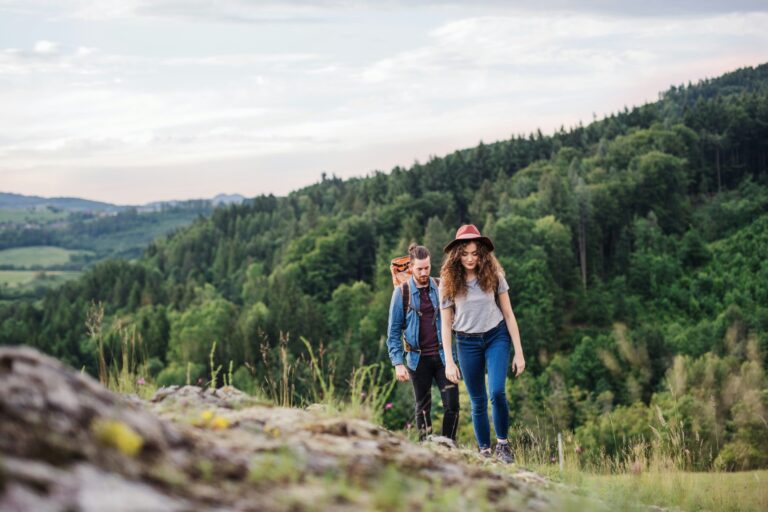 Une femme et un homme font une randonnée dans une forêt verdoyante.